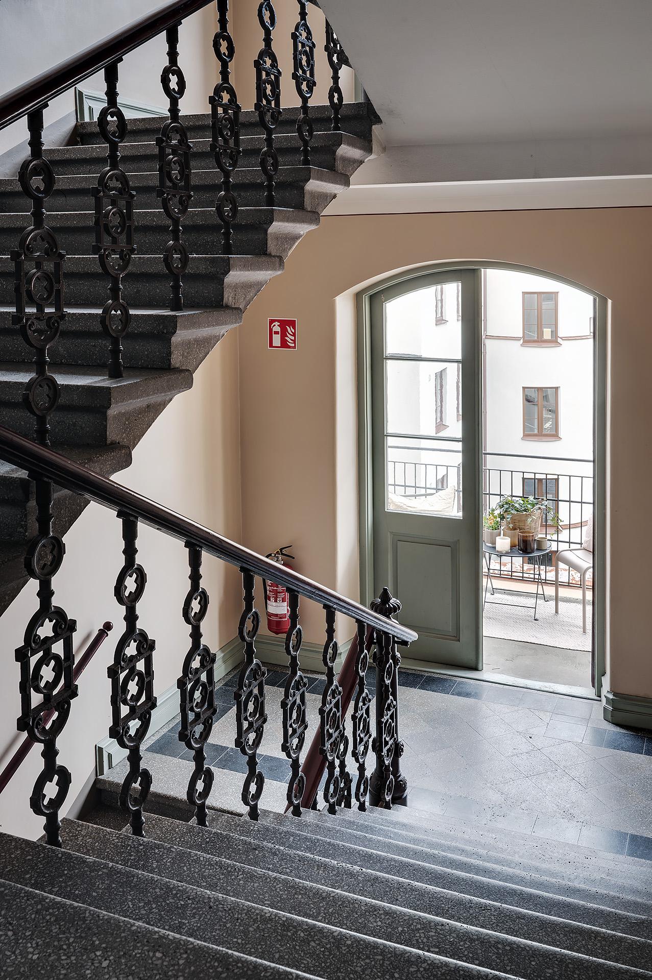 En smidesbalkong nås en halv trappa upp