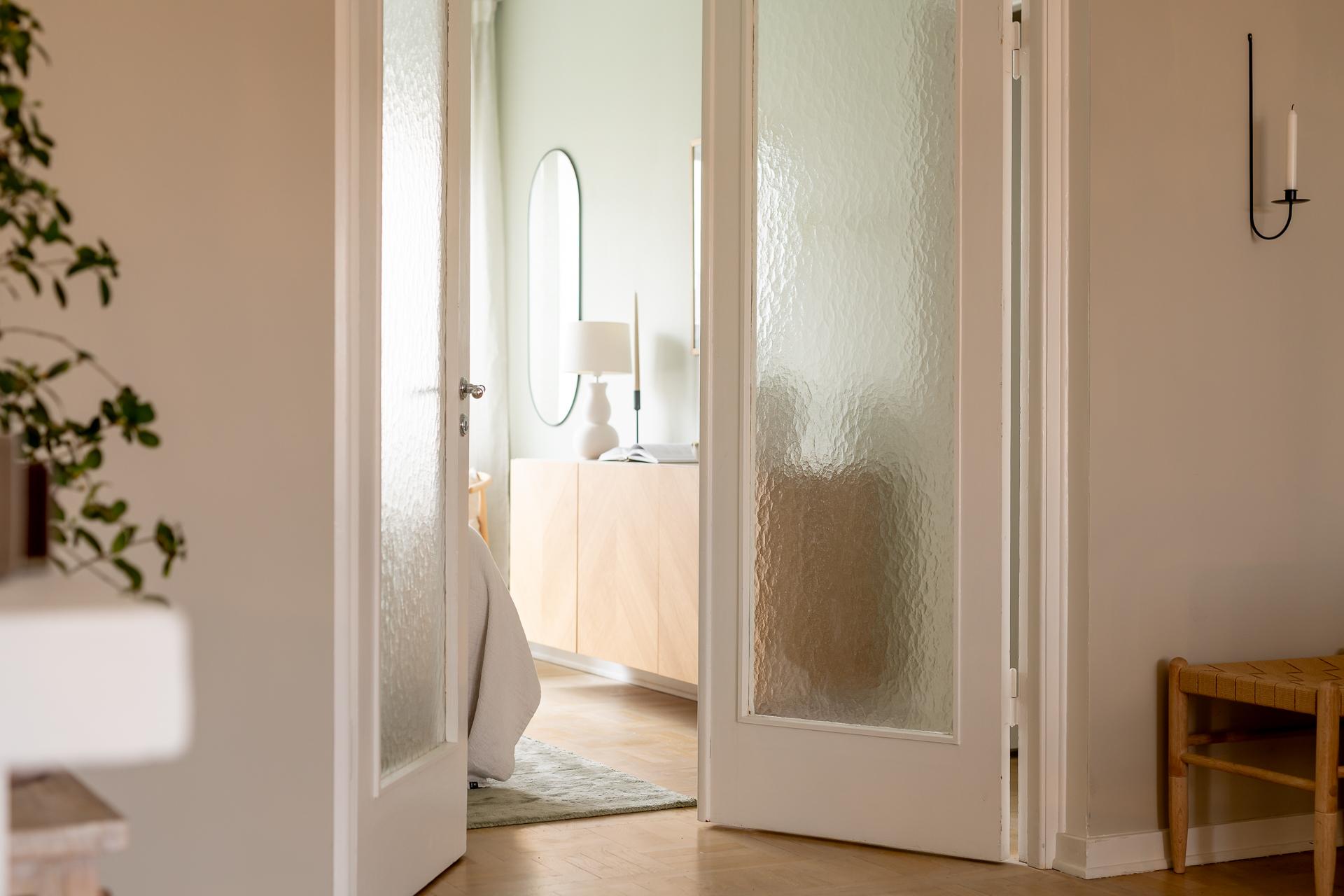 En dubbeldörr i glas från husets byggår leder oss in i  det större sovrummet