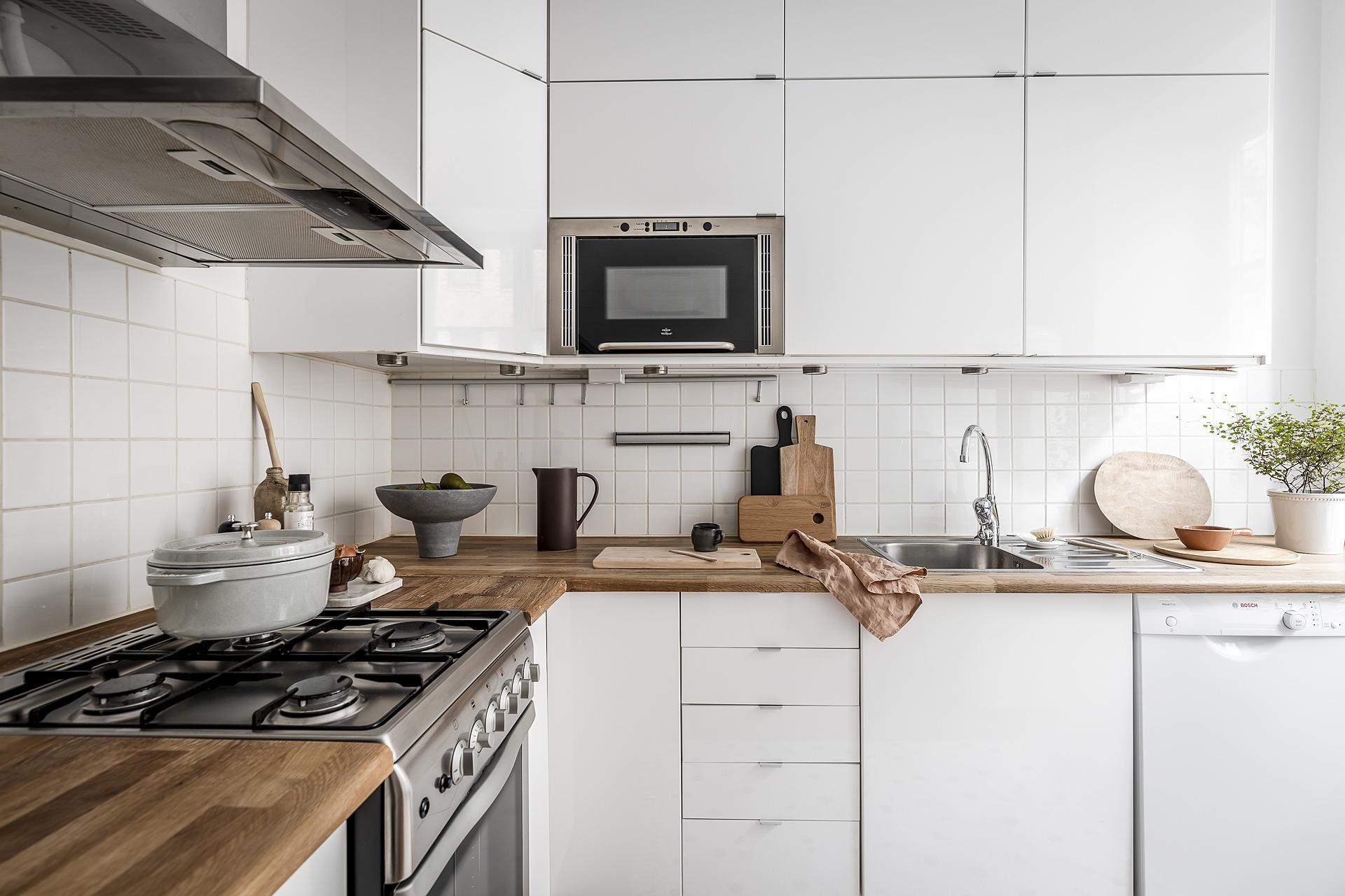 Köket har vita släta luckor och gasspis