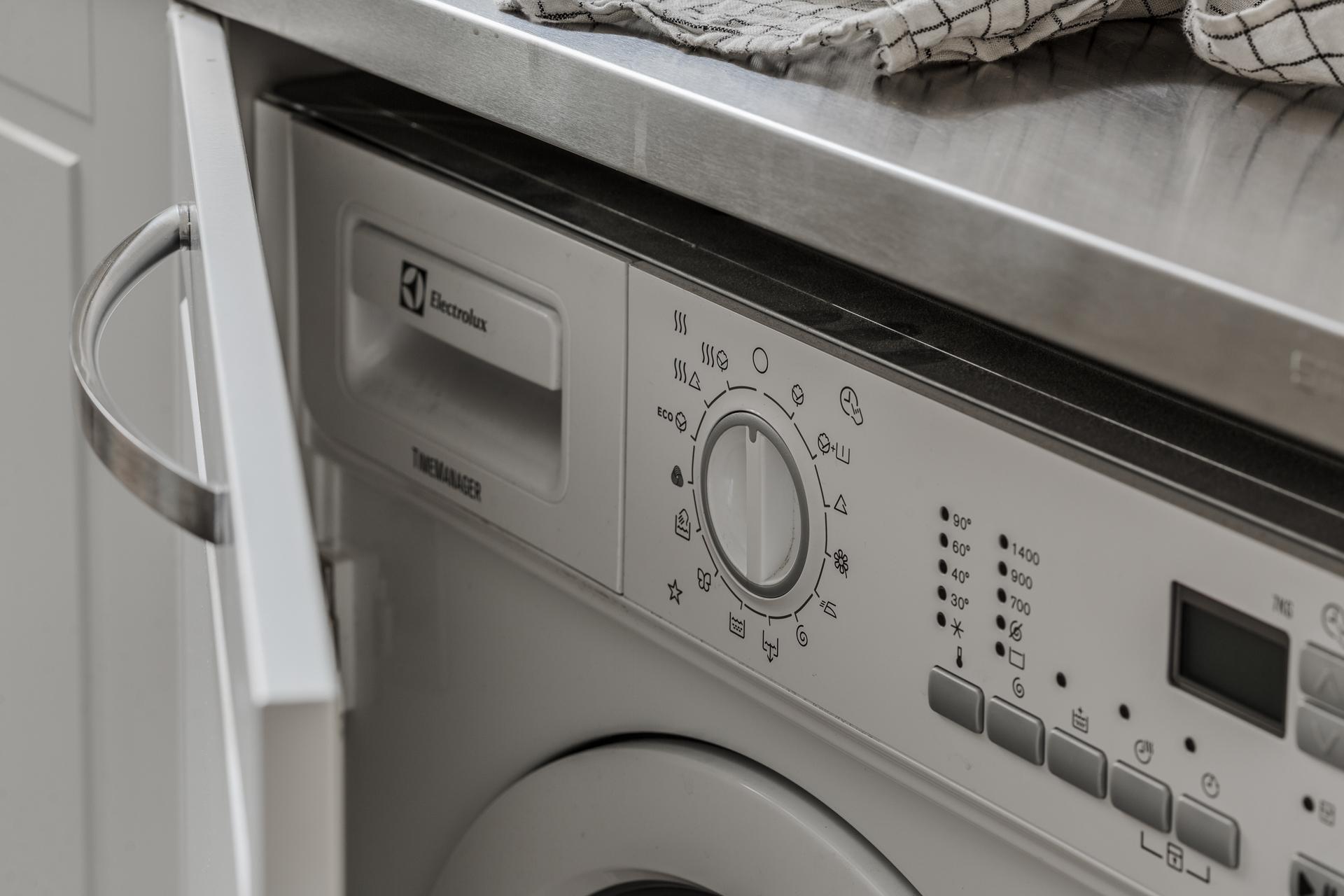 Lågupplöst Tvättmaskin finns praktiskt gömd bakom en kökslucka