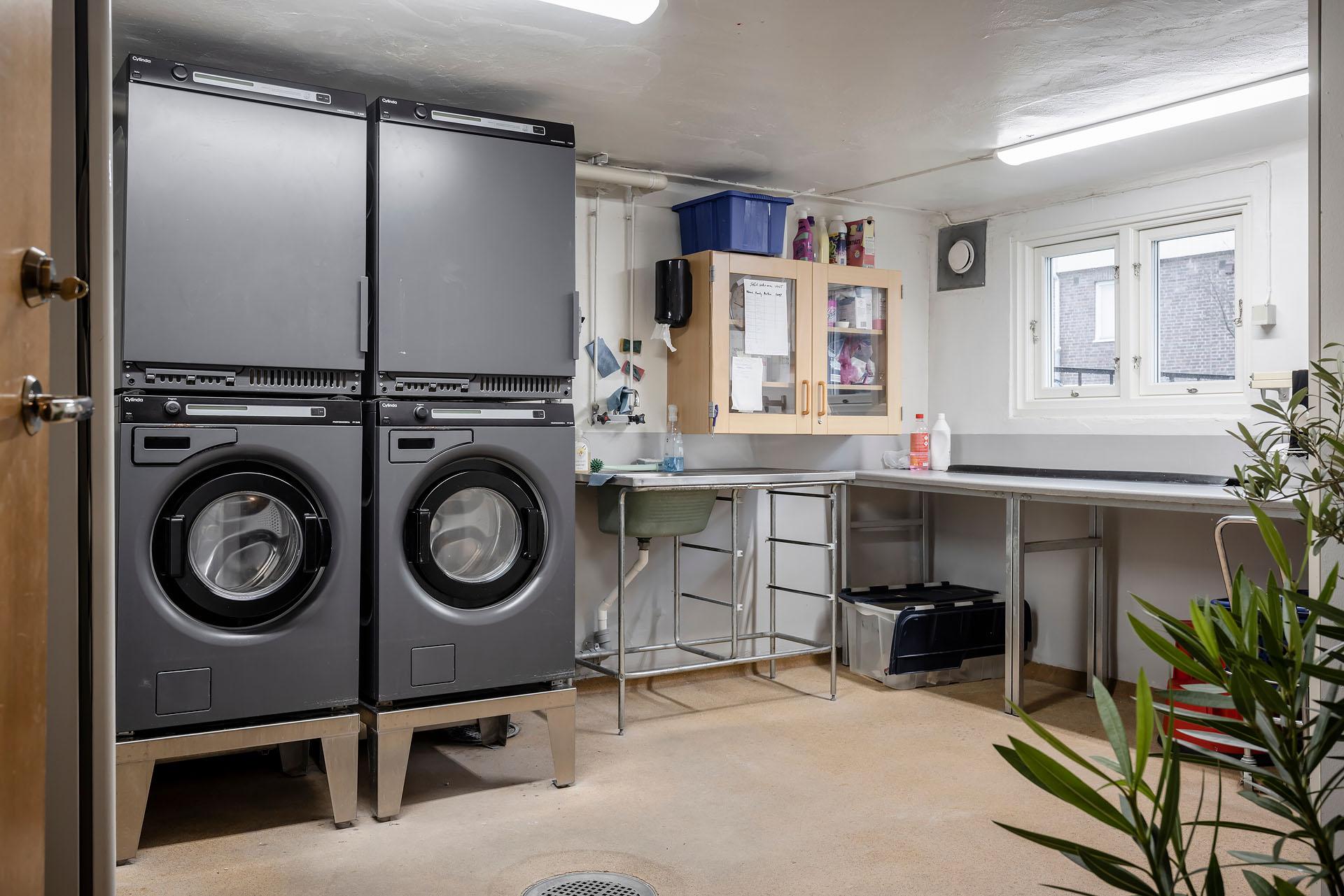 Tvättstuga med två tvättmaskiner, två tumlare och två torkskåp.