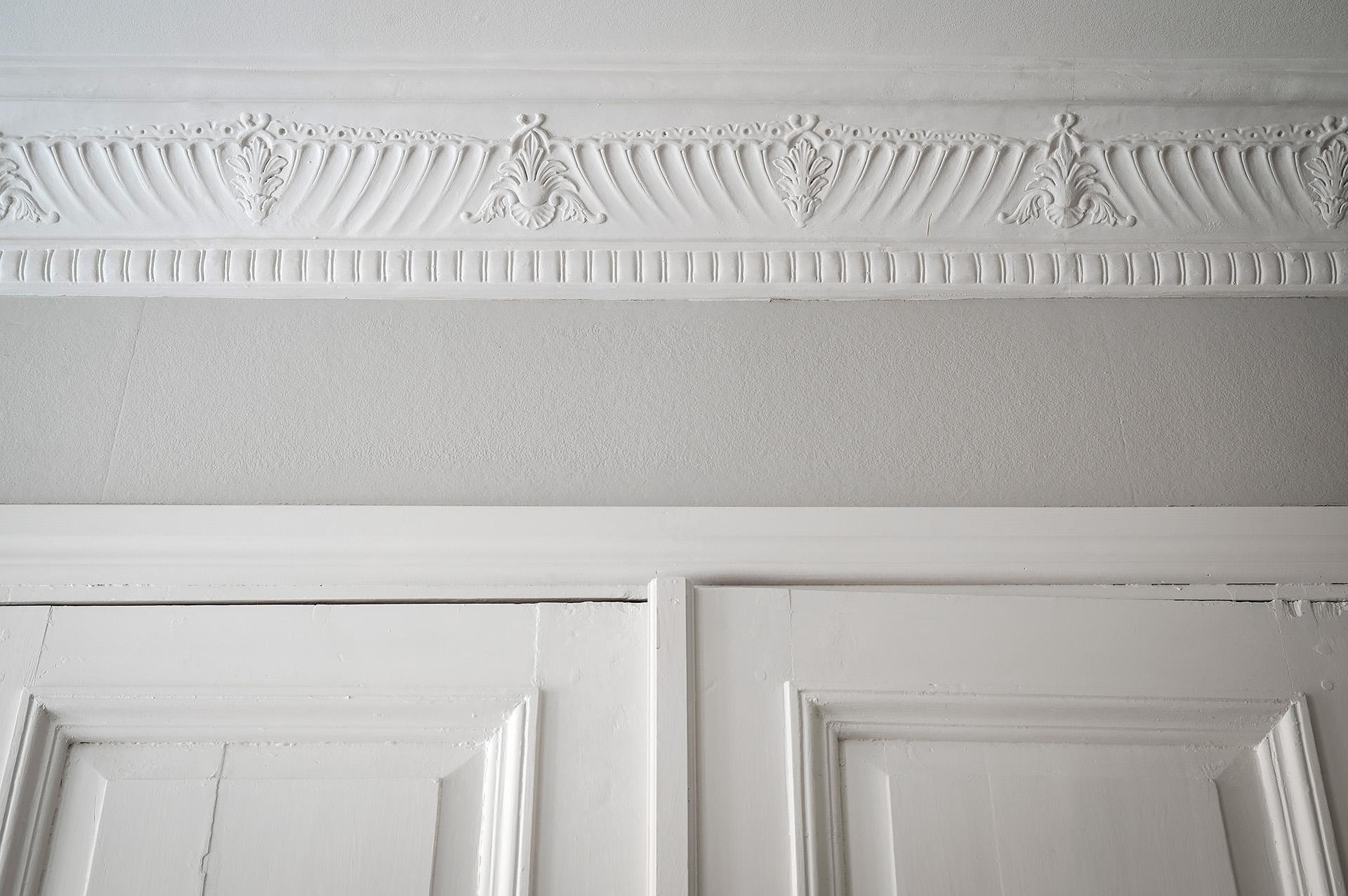 Bevarad stuckatur som framhävs av gråmålade väggar